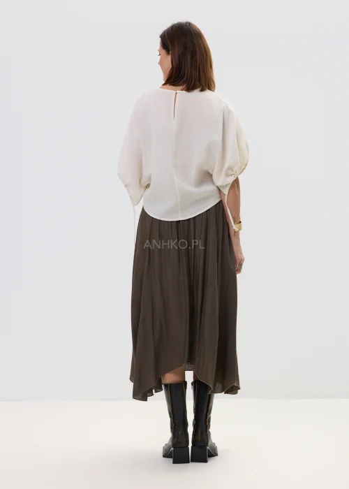Spódnica midi brązowa o zwiewnym, asymetrycznym kroju z delikatnym połyskiem, stylizowana z szerokim paskiem z ozdobną klamrą i botkami na obcasie.