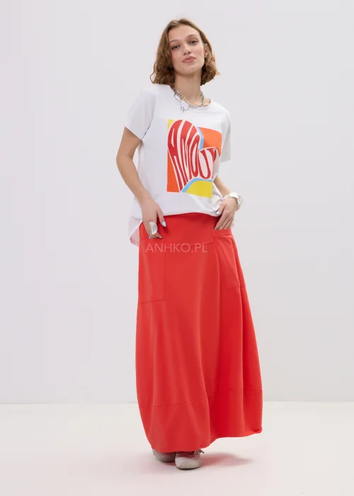 T-shirt oversize biały z kolorowym printem „Amour” w formie serca, luźny fason z krótkim rękawem – casualowa stylizacja z czerwono-pomarańczową spódnicą.