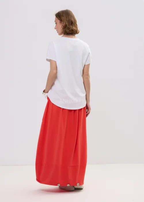 T-shirt oversize biały z kolorowym printem „Amour” w formie serca, luźny fason z krótkim rękawem – casualowa stylizacja z czerwono-pomarańczową spódnicą.