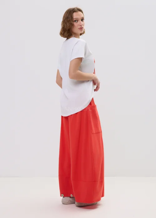 T-shirt oversize biały z kolorowym printem „Amour” w formie serca, luźny fason z krótkim rękawem – casualowa stylizacja z czerwono-pomarańczową spódnicą.