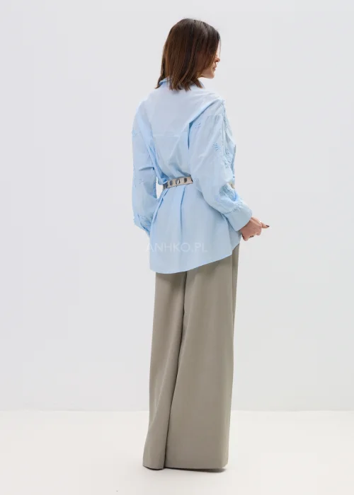 Koszula oversize błękitna z haftem kwiatowym, zapinana na guziki, z długim rękawem i klasycznym kołnierzem – elegancko-casualowa stylizacja z paskiem w talii.