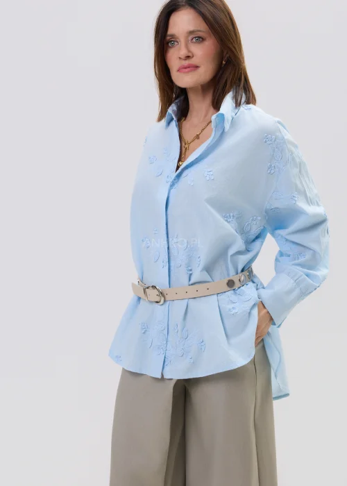 Koszula oversize błękitna z haftem kwiatowym, zapinana na guziki, z długim rękawem i klasycznym kołnierzem – elegancko-casualowa stylizacja z paskiem w talii.