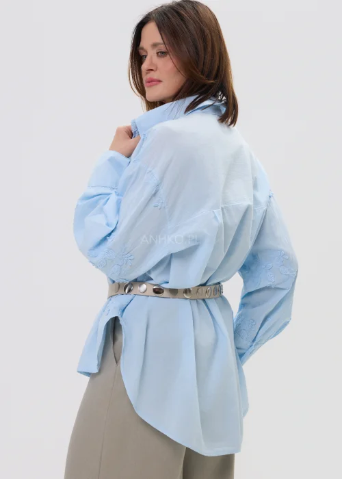 Koszula oversize błękitna z haftem kwiatowym, zapinana na guziki, z długim rękawem i klasycznym kołnierzem – elegancko-casualowa stylizacja z paskiem w talii.