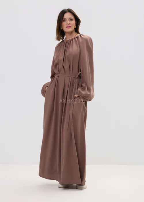 Sukienka maxi brązowa z marszczonym dekoltem i wiązaniem w talii, o płynnie opadającym fasonie – elegancka, minimalistyczna stylizacja z długim rękawem.