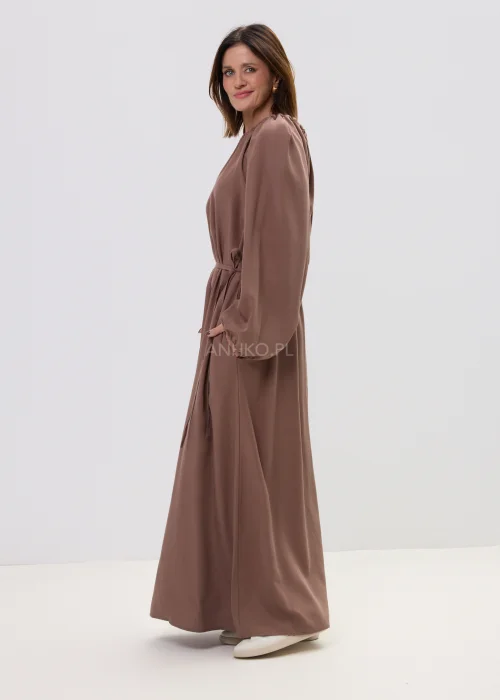 Sukienka maxi brązowa z marszczonym dekoltem i wiązaniem w talii, o płynnie opadającym fasonie – elegancka, minimalistyczna stylizacja z długim rękawem.