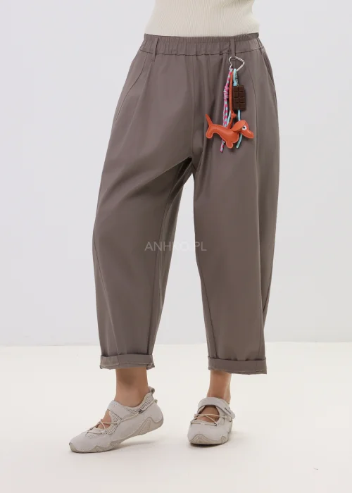 Spodnie damskie o luźnym kroju w kolorze taupe, z elastyczną talią i podwiniętymi nogawkami, ozdobione designerskim brelokiem – komfortowy model do codziennych stylizacji.