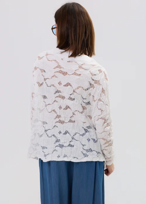 Biała bluzka damska z koronkową strukturą i długim rękawem, lekko transparentny materiał, styl casual.