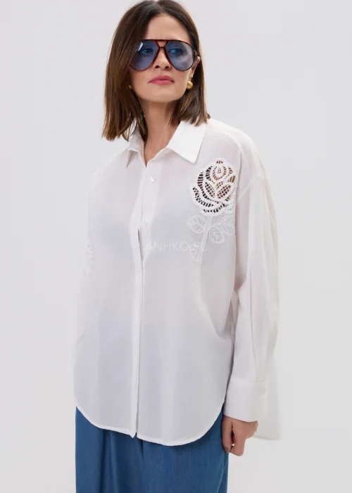 Biała koszula damska z haftowaną aplikacją róży, luźny fason, lekko transparentny materiał, elegancki styl.
