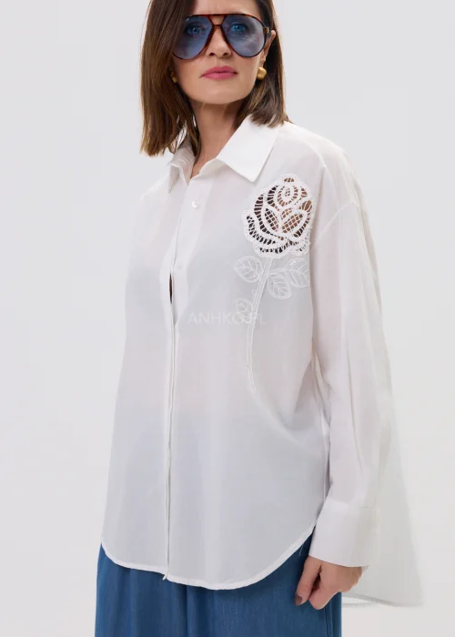 Biała koszula damska z haftowaną aplikacją róży, luźny fason, lekko transparentny materiał, elegancki styl.