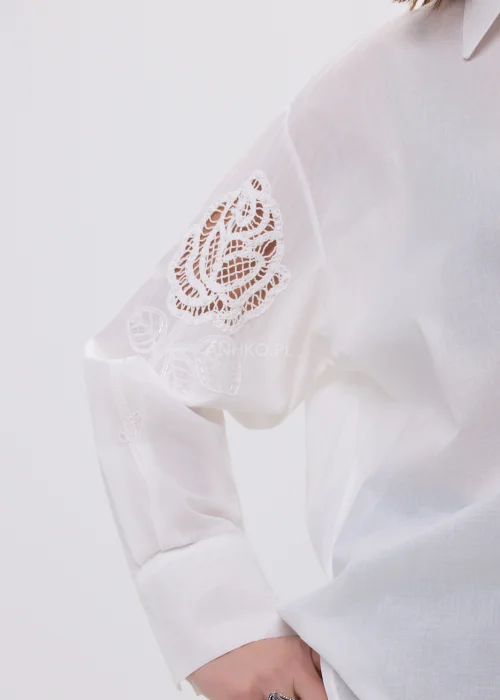 Biała koszula damska z haftowaną aplikacją róży, luźny fason, lekko transparentny materiał, elegancki styl.