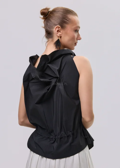 Czarna bluzka damska bez rękawów z ozdobnym marszczeniem przy dekolcie i regulacją w talii, zestawiona z plisowaną spódnicą.