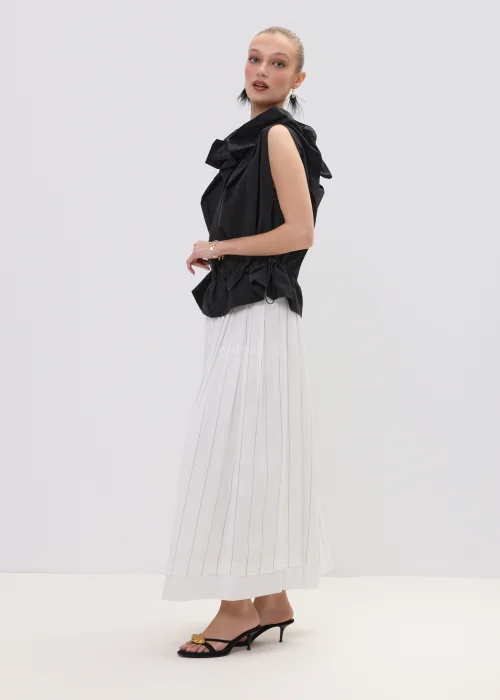 Czarna bluzka damska bez rękawów z ozdobnym marszczeniem przy dekolcie i regulacją w talii, zestawiona z plisowaną spódnicą.
