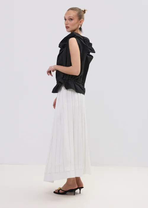 Czarna bluzka damska bez rękawów z ozdobnym marszczeniem przy dekolcie i regulacją w talii, zestawiona z plisowaną spódnicą.