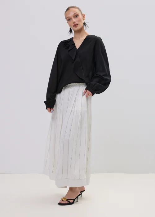 Czarna bluzka damska z kopertowym dekoltem i ozdobną falbaną, wykonana z lekkiego, półtransparentnego materiału o luźnym fasonie