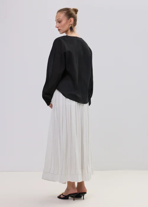 Czarna bluzka damska z kopertowym dekoltem i ozdobną falbaną, wykonana z lekkiego, półtransparentnego materiału o luźnym fasonie