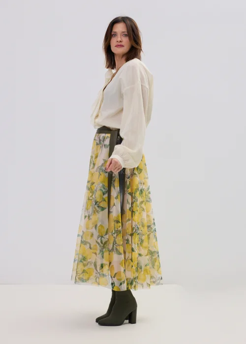 Kremowa bluzka damska z kopertowym dekoltem i ozdobną aplikacją kwiatową na ramieniu, o lekkim, zwiewnym materiale i eleganckim fasonie.