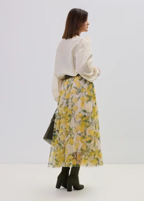 Kremowa bluzka damska z kopertowym dekoltem i ozdobną aplikacją kwiatową na ramieniu, o lekkim, zwiewnym materiale i eleganckim fasonie.