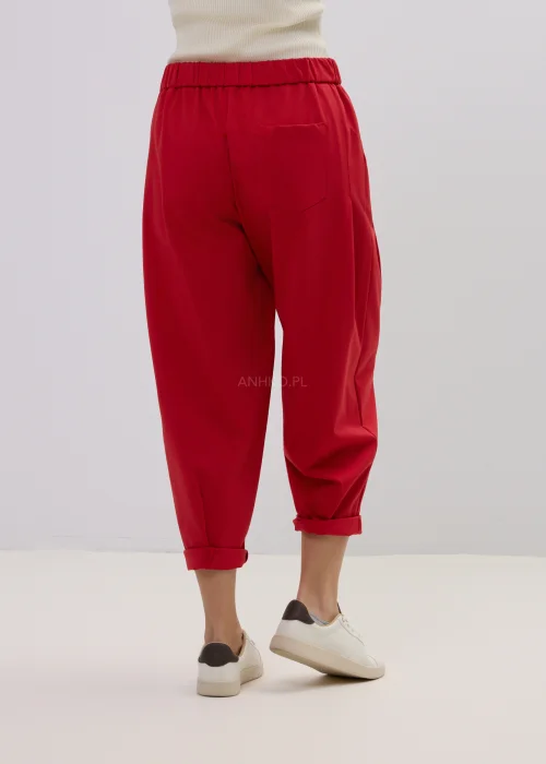 Czerwone spodnie damskie o luźnym kroju z podwiniętymi nogawkami, minimalistyczny fason, styl casual.