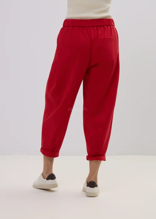 Czerwone spodnie damskie o luźnym kroju z podwiniętymi nogawkami, minimalistyczny fason, styl casual.