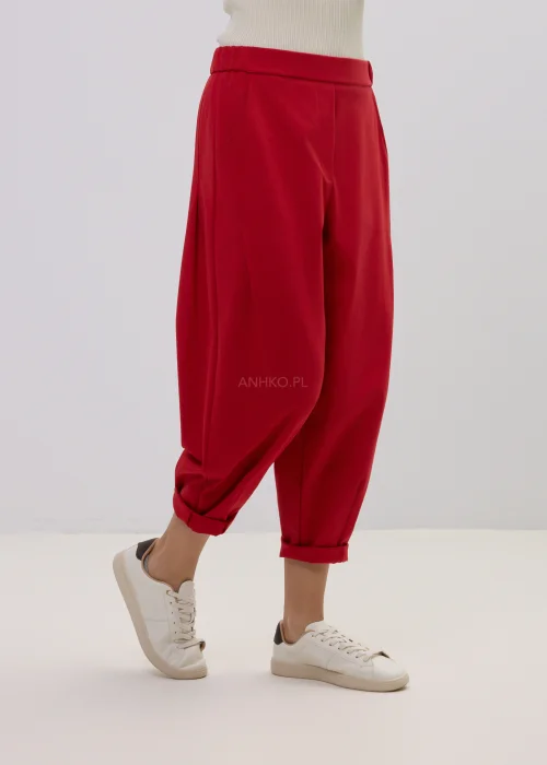Czerwone spodnie damskie o luźnym kroju z podwiniętymi nogawkami, minimalistyczny fason, styl casual.