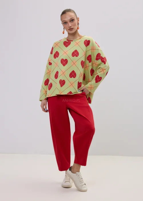 Luźna bluza damska oversize w kolorze limonkowym z czerwonym wzorem serc i geometryczną kratą, o szerokich rękawach i swobodnym fasonie.