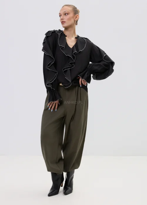 Czarna bluzka damska z falbanami i kontrastowym wykończeniem, luźny fason z długim rękawem, elegancka stylizacja ze spodniami w kolorze khaki.