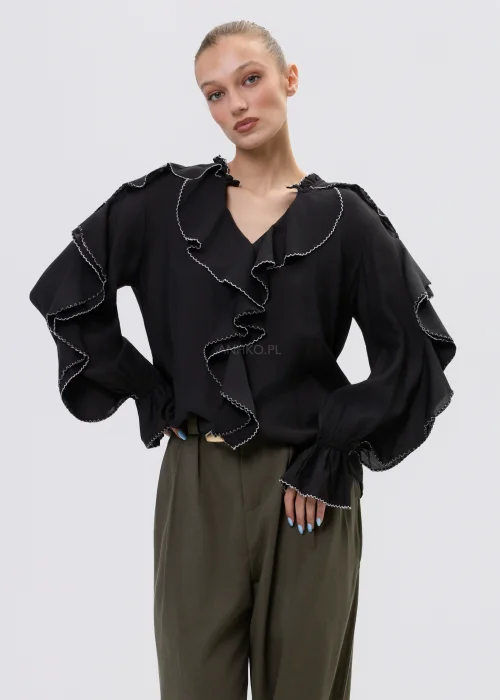 Czarna bluzka damska z falbanami i kontrastowym wykończeniem, luźny fason z długim rękawem, elegancka stylizacja ze spodniami w kolorze khaki.