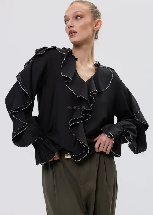 Czarna bluzka damska z falbanami i kontrastowym wykończeniem, luźny fason z długim rękawem, elegancka stylizacja ze spodniami w kolorze khaki.