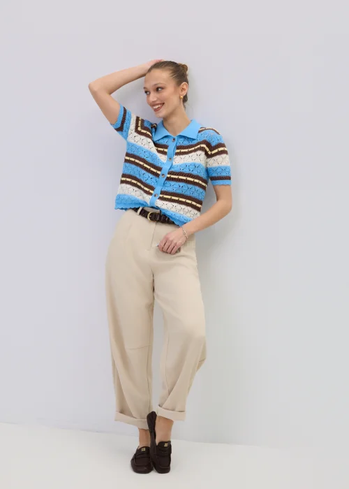 Ażurowy kardigan damski w paski w odcieniach błękitu i brązu z kołnierzykiem polo, stylizowany z beżowymi spodniami.