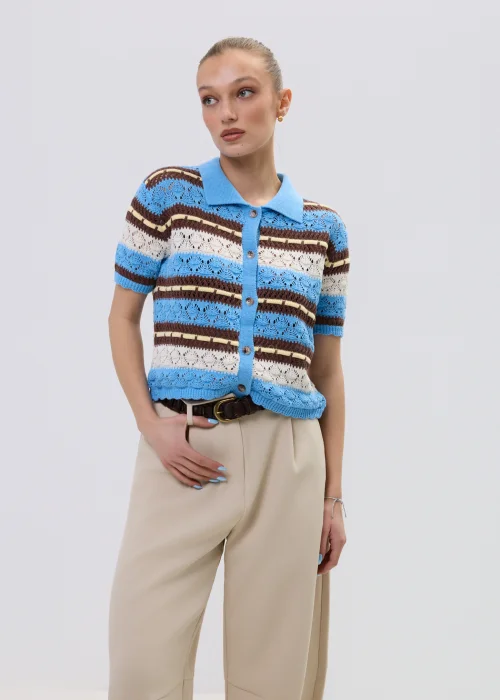 Ażurowy kardigan damski w paski w odcieniach błękitu i brązu z kołnierzykiem polo, stylizowany z beżowymi spodniami.