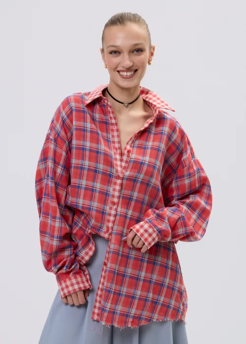 Koszula oversize w czerwono-niebieską kratę z postrzępionym wykończeniem, luźny fason z kołnierzem i guzikami, stylizacja casual z szerokimi spodniami.