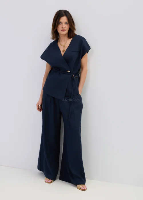 Granatowa kamizelka z dodatkiem lnu o kopertowym kroju, elegancki fason bez rękawów z paskiem w talii, stylizacja z szerokimi spodniami.