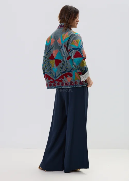 Welurowy żakiet w kolorze szaro-niebieskim z bogatym haftem w kwiaty i serca, oversize’owy fason, stylizacja casual z szerokimi spodniami.