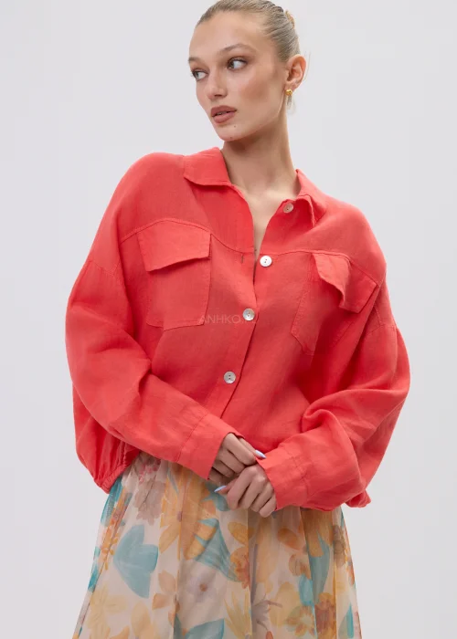 Koralowa koszula lniana damska oversize z kieszeniami i guzikami, lekka tkanina, stylizacja z pastelową spódnicą w kwiatowy wzór.