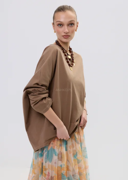 Brązowa bluzka oversize z długim rękawem o luźnym kroju, zestawiona z lekką spódnicą w pastelowy kwiatowy wzór.