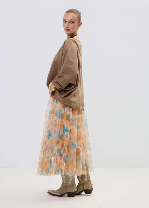 Brązowa bluzka oversize z długim rękawem o luźnym kroju, zestawiona z lekką spódnicą w pastelowy kwiatowy wzór.