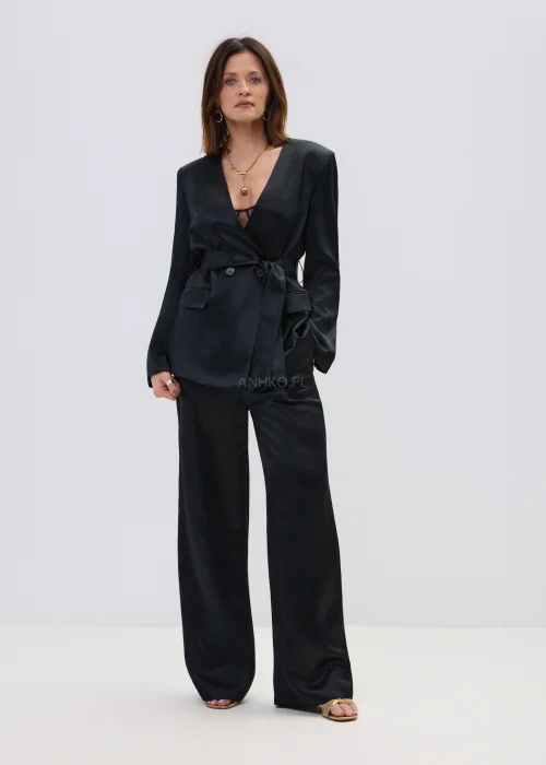 Czarny garnitur satynowy damski z wiązaną marynarką i szerokimi spodniami, elegancki zestaw o płynnej strukturze materiału.