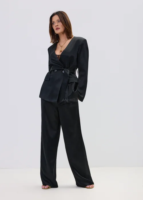 Czarny garnitur satynowy damski z wiązaną marynarką i szerokimi spodniami, elegancki zestaw o płynnej strukturze materiału.