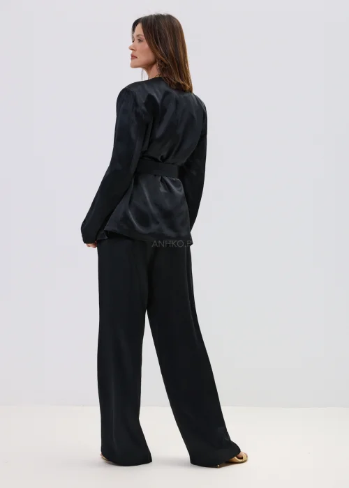 Czarny garnitur satynowy damski z wiązaną marynarką i szerokimi spodniami, elegancki zestaw o płynnej strukturze materiału.