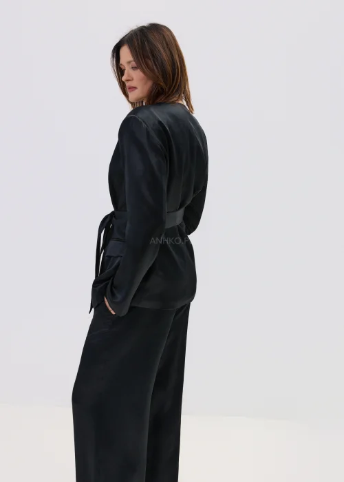 Czarny garnitur satynowy damski z wiązaną marynarką i szerokimi spodniami, elegancki zestaw o płynnej strukturze materiału.