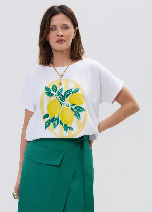 Biała koszulka z krótkim rękawem z nadrukiem cytryn i liści w stylu ilustracyjnym, zestawiona z zieloną spódnicą kopertową.