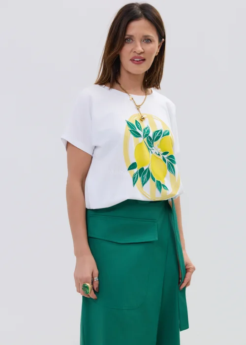Biała koszulka z krótkim rękawem z nadrukiem cytryn i liści w stylu ilustracyjnym, zestawiona z zieloną spódnicą kopertową.