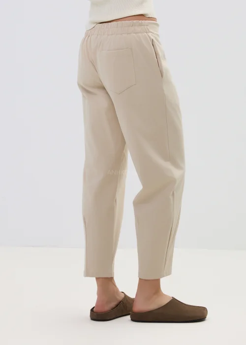 Beżowe spodnie damskie o prostym, lekko zwężanym kroju z wysokim stanem, minimalistyczny fason w elegancko-casualowej stylizacji.