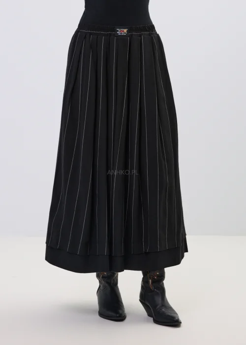 Czarna spódnica maxi z delikatnymi pionowymi prążkami, o rozkloszowanym fasonie i elastycznej talii, stylizowana z czarnymi botkami w stylu western.