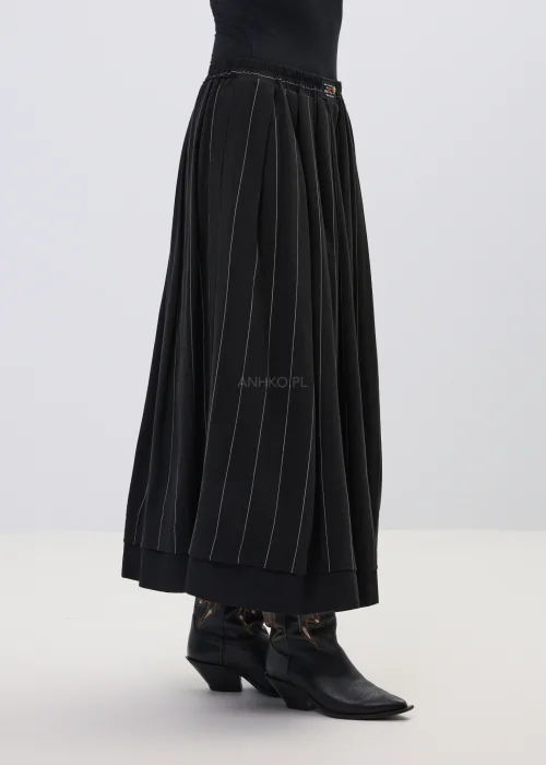 Czarna spódnica maxi z delikatnymi pionowymi prążkami, o rozkloszowanym fasonie i elastycznej talii, stylizowana z czarnymi botkami w stylu western.