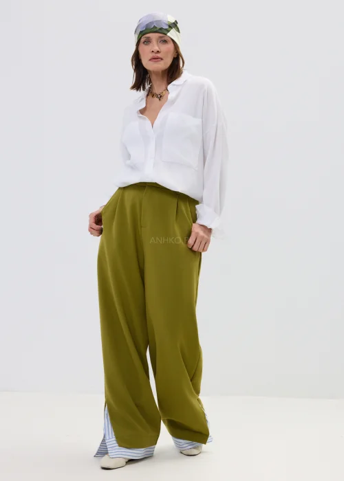 Biała koszula oversize z kieszeniami na piersi, noszona z oliwkowymi spodniami i chustą na głowie w kwiatowy wzór.