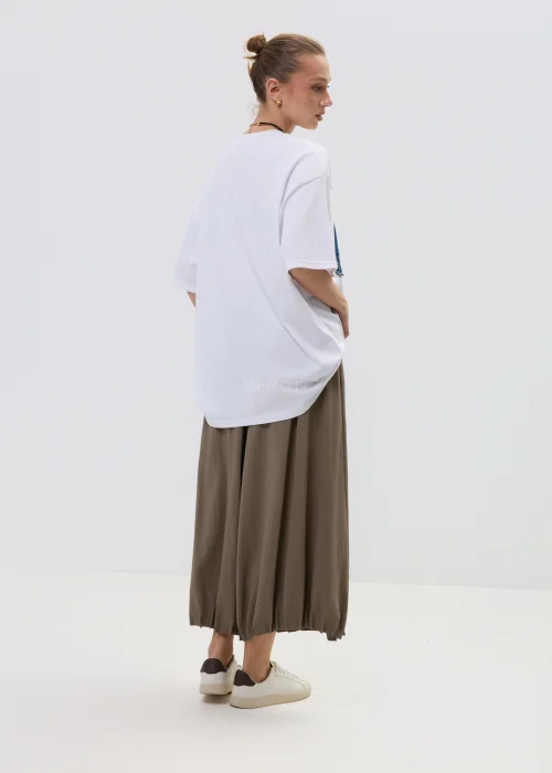 Biała bluzka oversize z dużą aplikacją dziewczynki w stylu cartoon z jeansową kokardą i zdobieniami, stylizowana ze spódnicą w casualowym looku.