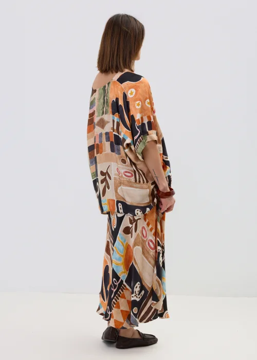 Wzorzysta bluzka oversize w geometryczny print w odcieniach beżu, czerni i pomarańczu, z luźnym rękawem, stylizowana w komplecie ze spódnicą w artystycznym looku.