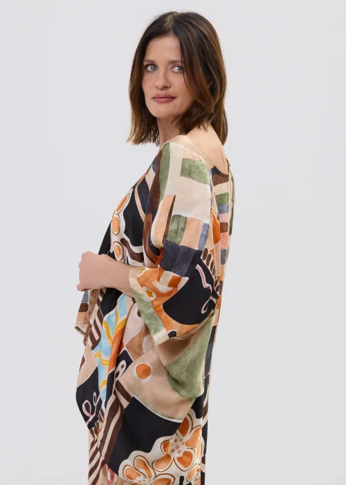 Wzorzysta bluzka oversize w geometryczny print w odcieniach beżu, czerni i pomarańczu, z luźnym rękawem, stylizowana w komplecie ze spódnicą w artystycznym looku.