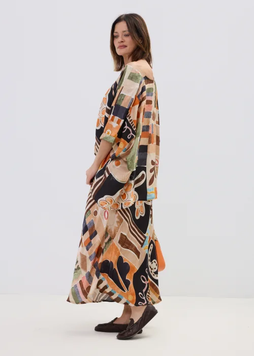 Wzorzysta bluzka oversize w geometryczny print w odcieniach beżu, czerni i pomarańczu, z luźnym rękawem, stylizowana w komplecie ze spódnicą w artystycznym looku.